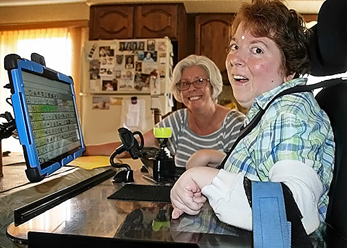 AAC Assistive Tech - Tess is happy learning to use her AAC device while her assistive technology specialist looks on. 